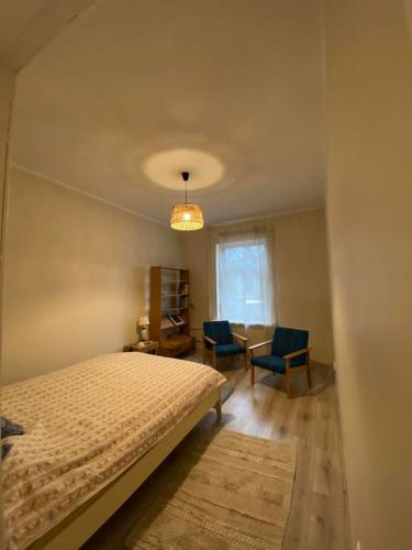 a bedroom with a bed and two chairs and a table at Cosy place in historic building in Šilutė