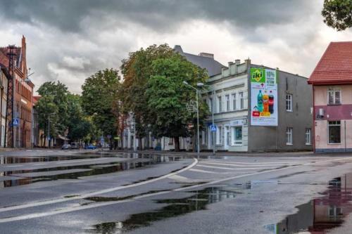an empty city street with puddles of water on the road at Cosy place in historic building in Šilutė