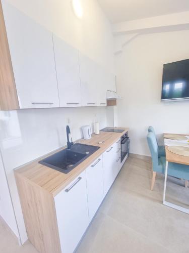 a kitchen with white cabinets and a sink and a table at Apartman Natali in Kremena