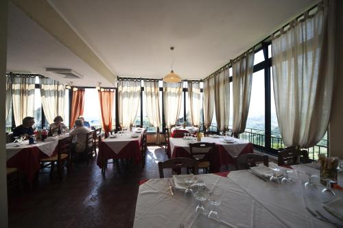 uma sala de jantar com mesas, cadeiras e janelas em Locanda Ristorante Bar Il Faro em Guiglia