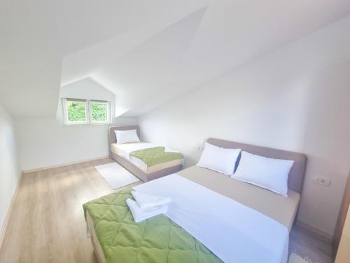 a white bedroom with a large bed and a window at Apartman Natali in Kremena