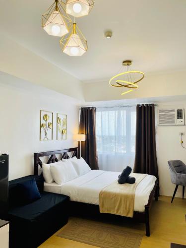 a bedroom with a large bed and a chandelier at Spacious Stylish Studio Unit at Avida Aspira Tower 1 in Cagayan de Oro
