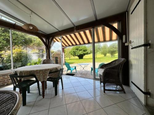 une véranda avec une table et des chaises dans l'établissement La Jarisse, à Saint-Martin-de-Fressengeas