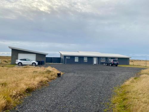 a car parked in front of a building on a gravel road at Hamar - Puffin Cottages & Rooms in Hvolsvöllur