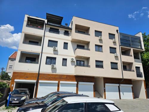 a tall building with cars parked in front of it at Apartman Sky in Sremska Mitrovica
