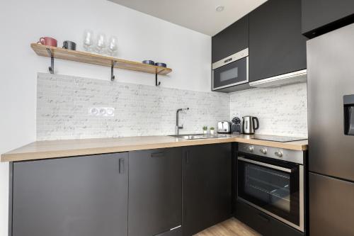 une cuisine avec des armoires noires et un comptoir dans l'établissement Modern & Pleasant Flat in the Heart of the 15th, à Paris