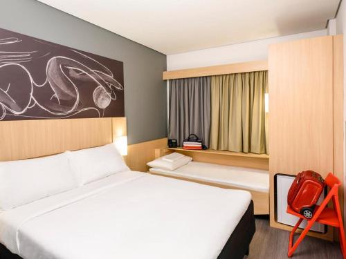 um quarto de hotel com duas camas e uma cadeira vermelha em ibis Bacabal em Bacabal