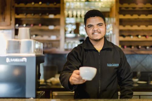 a man holding a cup in a coffee shop at Garden Route Ilita Lodge in Groot Brak Rivier