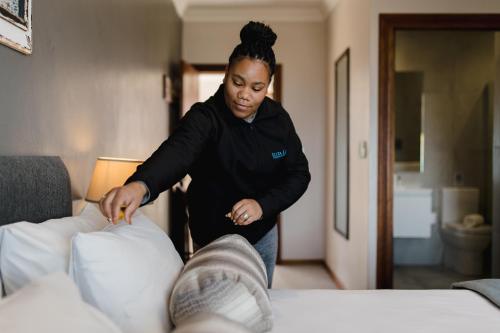 a woman is putting pillows on a bed at Garden Route Ilita Lodge in Groot Brak Rivier