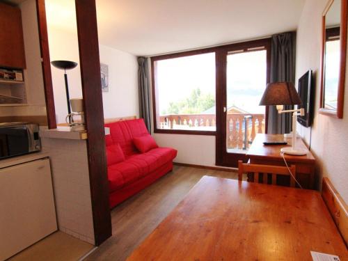 - un salon avec un canapé rouge et une grande fenêtre dans l'établissement Appartement cosy 2 pièces, 6 pers, Alpe d'Huez - proche pistes et commerces - FR-1-405-52, à L'Alpe-d'Huez