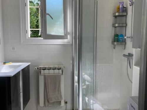 une salle de bain blanche avec une douche et un lavabo dans l'établissement Appartement pieds dans l'eau à Royan avec jardin et équipements complets - FR-1-494-130, à Royan