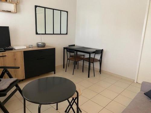 - un salon avec une table, des chaises et une télévision dans l'établissement Appartement pieds dans l'eau à Royan avec jardin et équipements complets - FR-1-494-130, à Royan