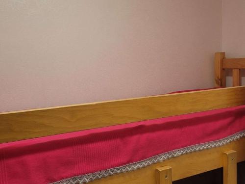 a wooden bed with red and pink sheets on it at Studio cosy avec jardinet, près des pistes et centre, 4/5 pers, Le Grand-Bornand - FR-1-458-184 in Le Grand-Bornand