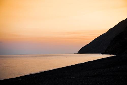 a beach at sunset with the ocean in the background at Villa Mareblu Luxury Holiday Apartment direttamente sul mare in Stromboli
