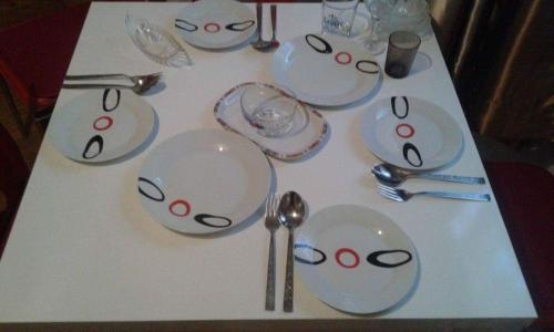 een tafel met witte borden, lepels en vorken bij Апартаменти Viviana in Plovdiv