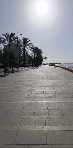 a stone walkway next to the ocean with palm trees at Blended in Calafell