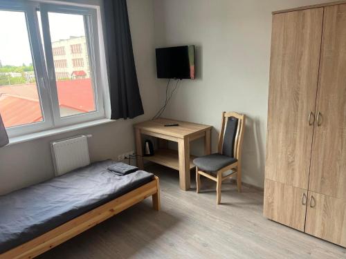 Schlafzimmer mit einem Bett, einem Schreibtisch und einem Fenster in der Unterkunft OSPER Rooms in Łomża
