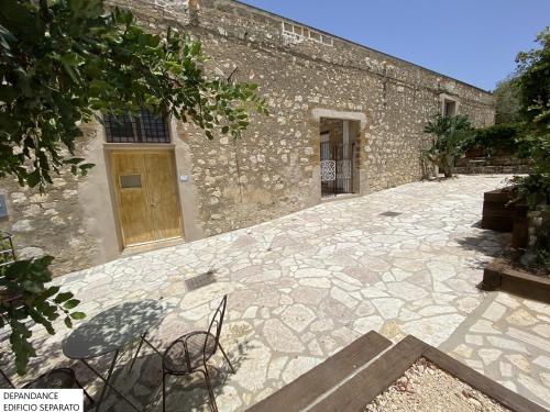 a stone patio with chairs in front of a building at Tenute Plaia Agriturismo in Scopello