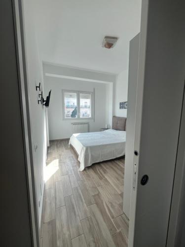 ein weißes Schlafzimmer mit einem Bett und Holzboden in der Unterkunft Calalula Apartment Palermo in Palermo
