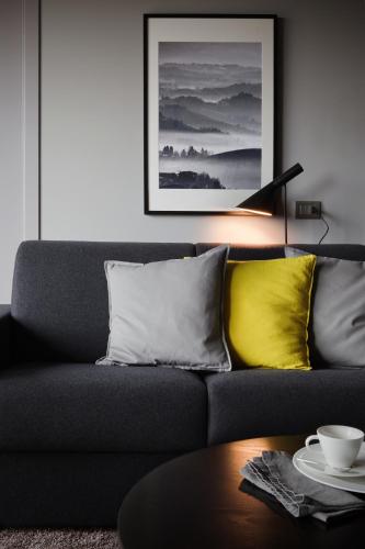 a living room with a gray couch with yellow pillows at Arborina Relais in La Morra