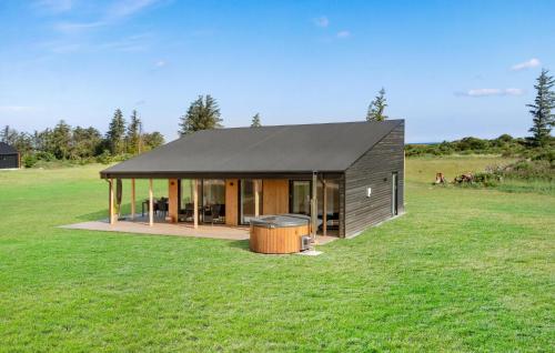 ein Haus mit einem schwarzen Dach auf einem grünen Feld in der Unterkunft Stunning Home In Hjørring With Wifi in Hjørring