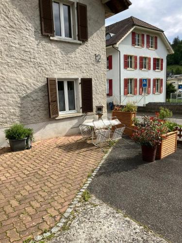 a house with two chairs and flowers in front of it at Au numéro 12 in Courchavon