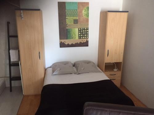 une chambre avec un lit et deux armoires en bois dans l'établissement studio meublé et équipé, à Bellegarde