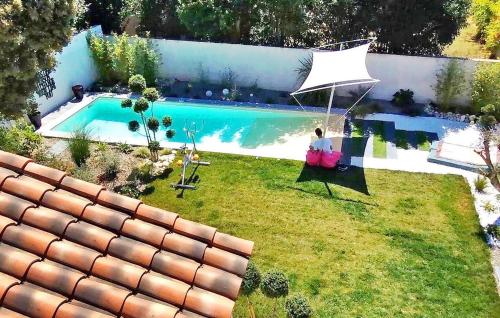 une personne assise dans une chaise à côté d'une piscine dans l'établissement La Villa De Notre Dame, à Châteaurenard