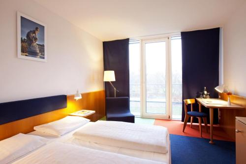 a hotel room with two beds and a desk at Vienna House by Wyndham Havelufer Potsdam in Potsdam