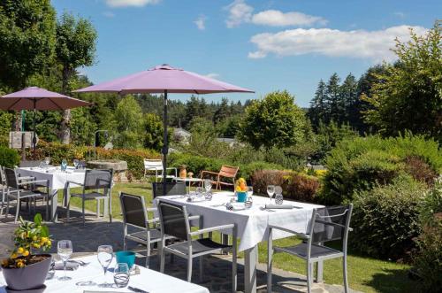 a group of tables with chairs and an umbrella at Bel Horizon in Le Chambon-sur-Lignon