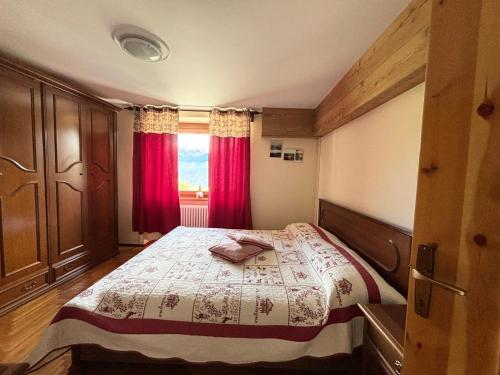 a bedroom with a large bed with red curtains at Maison Jenny in Aosta