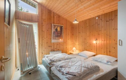 a bedroom with a large bed in a wooden wall at Stunning Home In Brovst With Sauna in Brovst