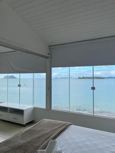 a bedroom with a bed and a view of the ocean at Búzios casa pé na areia em condomínio beira mar in Búzios