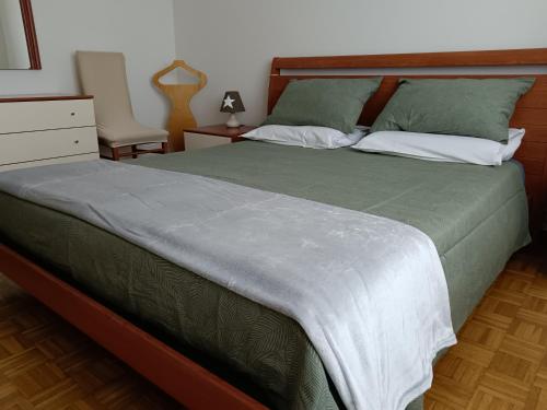 1 dormitorio con 1 cama con sábanas verdes y silla en Appartamento Casa Alice en Omegna