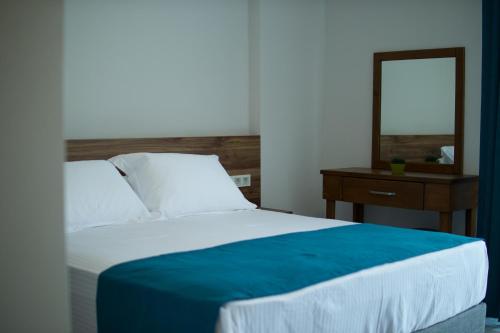 a bed with a blue blanket and a mirror at Troilus Park House in Eceabat