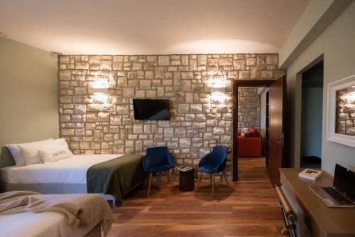 a bedroom with two beds and a stone wall at Rouista Tzoumerka Resort in Vourgareli