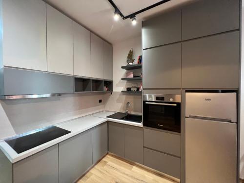 Una cocina con gabinetes blancos y electrodomésticos de acero inoxidable. en Tirana LUX Apartments, en Tirana