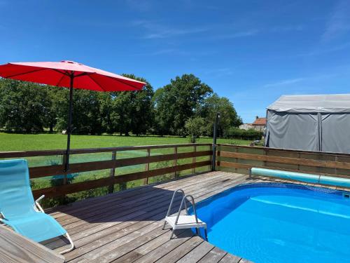a deck with a chair and an umbrella next to a pool at Bungalow accueillant à Saint-Pardoux avec piscine partagée in Saint-Pardoux