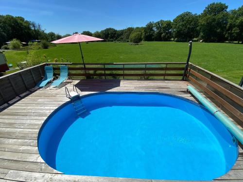 una gran piscina azul en una terraza de madera en Bungalow de 2 chambres avec piscine partagee jardin clos et wifi a Saint Pardoux, en Saint-Pardoux