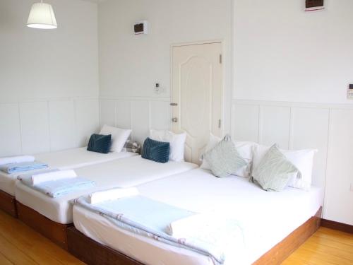 two beds in a room with white walls at Thirty Tree Garden House in Chumphon