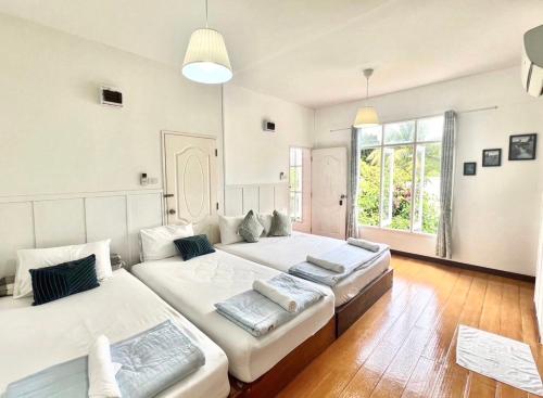 a bedroom with two beds and a large window at Thirty Tree Garden House in Chumphon