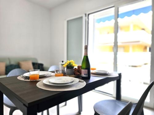 a table with a bottle of wine and a glass of orange juice at Grey House 5 100mt dal mare in Tortoreto Lido