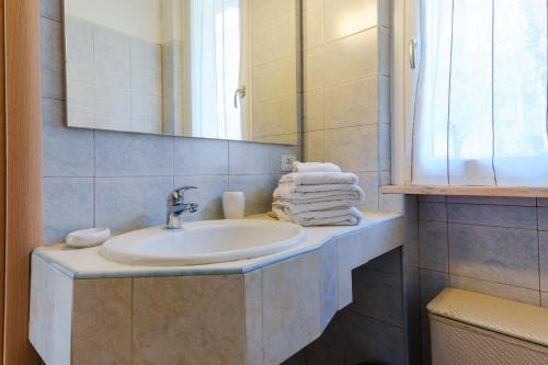 een badkamer met een wastafel, een spiegel en handdoeken bij Villa Oliveto apartments in Oliveto Lario