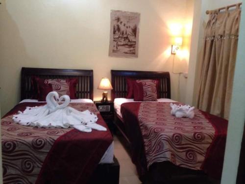 two beds with swans on them in a hotel room at Sakura Wood House in Luang Prabang