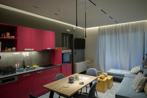 a kitchen and living room with red cabinets and a table at Antinea Olympian Villa in Olympia