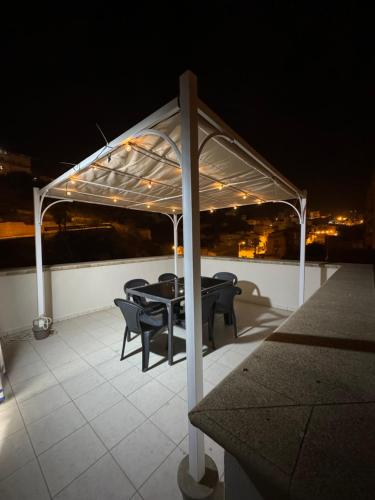 un gazebo con tavolo e sedie su un tetto di notte di Amunì in terrazza a Porto Empedocle