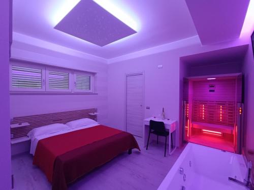 I due piccioncini suite في غروتاميناردا: غرفة نوم مع سرير ومكتب مع ضوء احمر