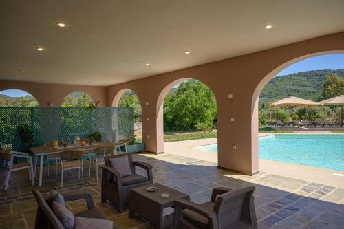 a patio with a table and chairs and a pool at Antinea Olympian Villa in Olympia