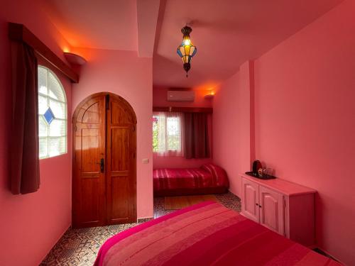 a bedroom with pink walls and a wooden door at Dar Fatima in Chefchaouene