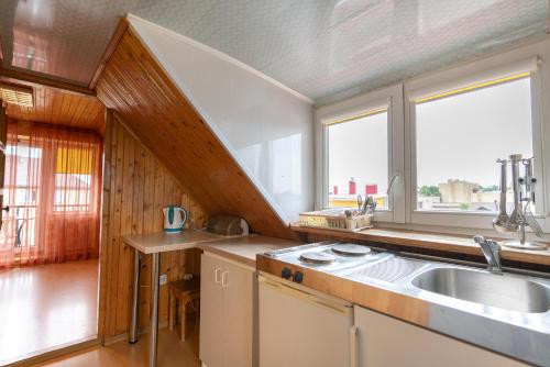 a kitchen with a sink and a large window at Po Kastonu & SPA in Palanga